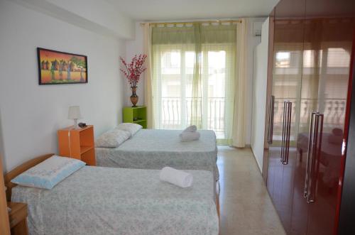 a hotel room with two beds and a window at Taormina Bay Lucia's House 3 in Nizza di Sicilia