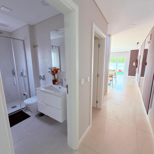 a white bathroom with a sink and a toilet at MoradiaT4 com piscina in Arrentela