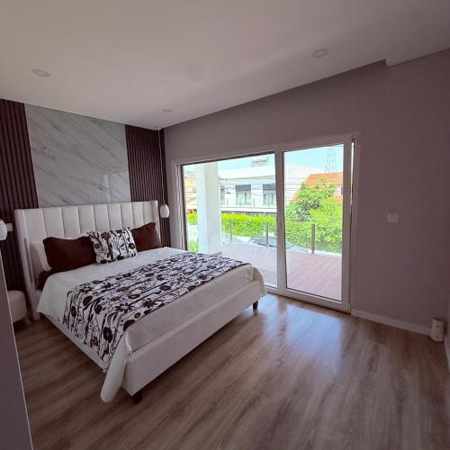 a bedroom with a bed and a large sliding glass door at MoradiaT4 com piscina in Arrentela