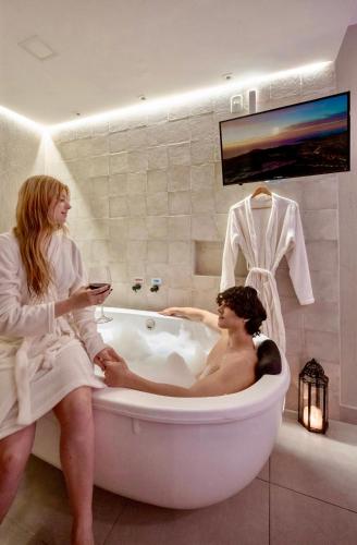 two women sitting in a bath tub in a bathroom at Pousada Rosa Karioka in Praia do Rosa