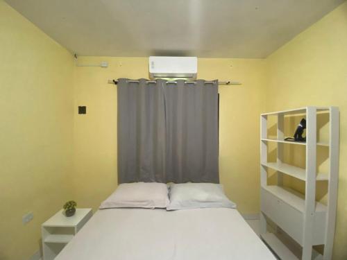a small bedroom with a bed and a window at Casa Camargo - com mercado na frente in Campo Grande