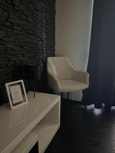 a room with a chair and a table with a picture at Black&White Deluxe in Miskolc