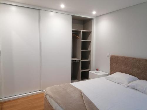 a bedroom with white walls and a bed and a closet at Casa Gonzaga in Amarante