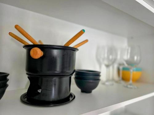 a black bucket of chopsticks on a shelf with wine glasses at Flat no Condomínio Monte Castelo ao lado da área de lazer, Gravatá-PE in Gravatá