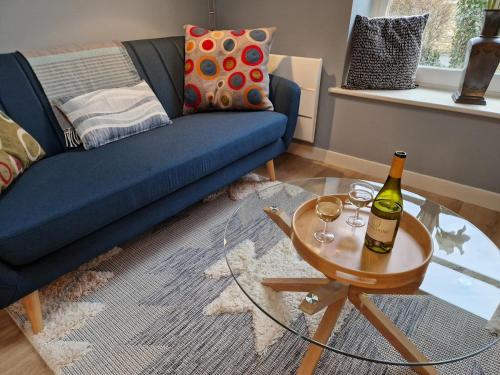 Le ChalardにあるCozy small houseの青いソファとテーブルの上にワインのボトルがあるリビングルーム