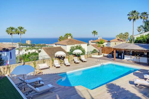 a swimming pool with chairs and the ocean in the background at Home4u Mediterranean Sea Views Villa Alkaff in Manilva