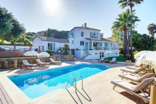 a swimming pool with chairs and a house at Home4u Mediterranean Sea Views Villa Alkaff in Manilva