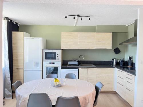 een keuken met een tafel met stoelen en een witte keuken bij A l'orée des bois in Égat