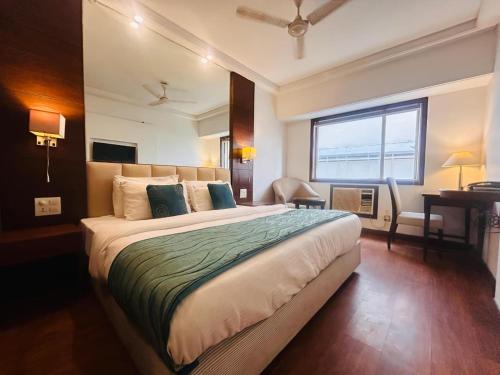 a bedroom with a large bed with a desk and a window at Prime Park Top Rated Property in Haridwar in Haridwār