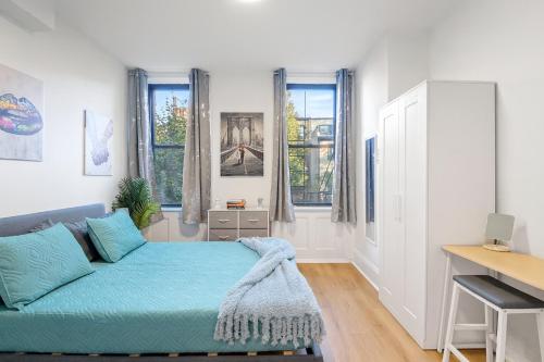 a bedroom with a couch and a desk and windows at Hoboken Hideaway - Walk to Transit - 15 Mins to NYC in Hoboken