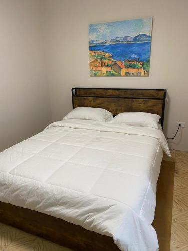 a bed with white sheets and a painting on the wall at Mereri downtown appartments in Oranjestad
