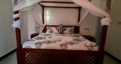 een slaapkamer met een hemelbed bij Malkia Apartment in Kibigija