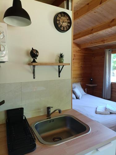 a bathroom with a sink and a bed and a clock at Camping Les Rochelles in Prunay-Cassereau