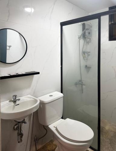 a bathroom with a toilet and a sink and a shower at D'ELEMENTS HOTEL AND DORMITORY in Laoag