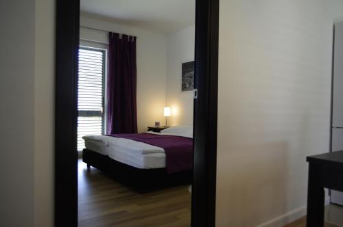 a bedroom with a bed and a window and a mirror at Apartments Santis10 in Baška
