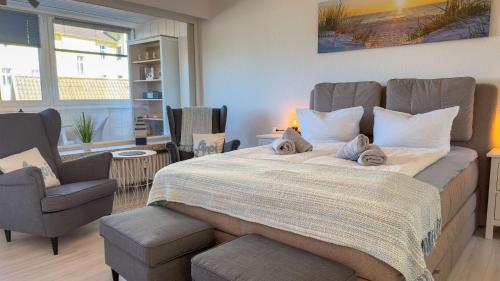 ein Schlafzimmer mit einem großen Bett und zwei Stühlen in der Unterkunft Seedeich Meehrblick Alte Liebe in Cuxhaven