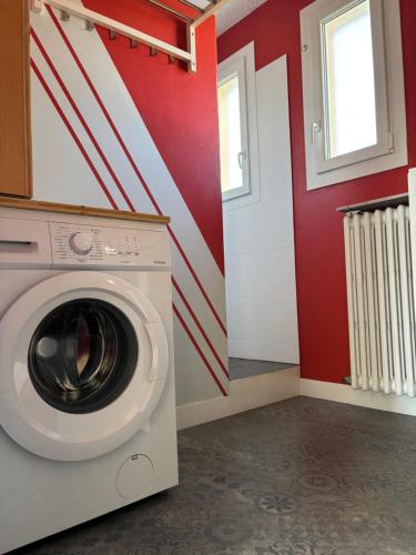 a washing machine in a laundry room with red walls at La parenthèse in Clairvaux-les-Lacs