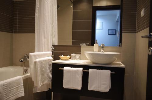 a bathroom with a sink and a tub with towels at Apartments Santis10 in Baška