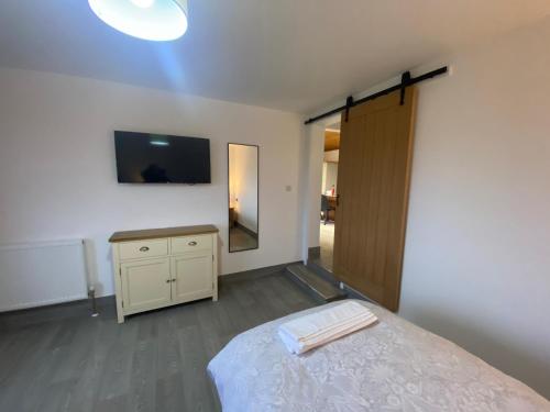 a bedroom with a bed and a dresser and a television at POPPY LUXURY LODGE Sleeps 8 at Fairview Farm, Ravenshead, Nottingham Near Sherwood Forest, Dog Friendly, Farm Stay great for wedding groups, families, Hen Do's, friends gatherings with amazing views in Blidworth