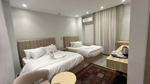 a hotel room with two beds and a table at Saloumy pyramids hotel in Nazlat as Sammān