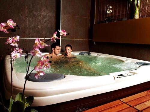 two people sitting in a bath tub at Gran Chalet Hotel & Petit Spa in Vielha