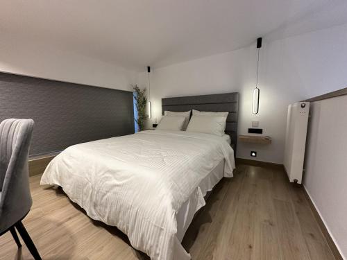 een slaapkamer met een groot wit bed en een stoel bij TrikalaBnB - Prime Loft 2 in Tríkala