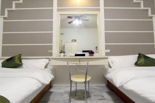 a room with two beds and a table and a mirror at 陶陶居商旅 Tautauchu Hotel in Hualien City