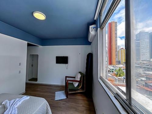 1 dormitorio con techo azul y ventana grande en Loft em Belém at Doca-Umarizal, Bairro nobre central, en Belém