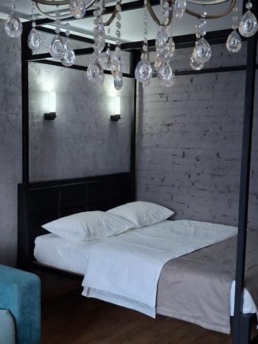 a bedroom with a bed with white sheets and lights at Дизайнерская квартира в ста метрах от городского парка in Petropavlovsk