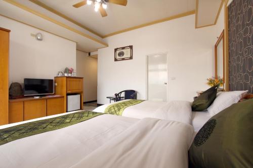 a hotel room with two beds and a flat screen tv at 陶陶居商旅 Tautauchu Hotel in Hualien City