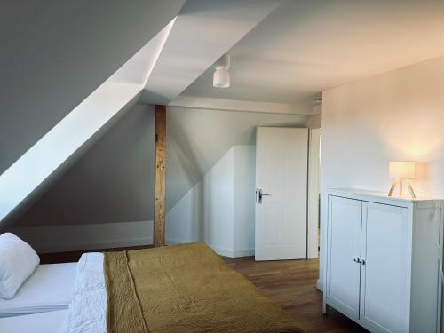 a attic bedroom with a bed and a white cabinet at Dr. Bockemüller Appartements in Sickte