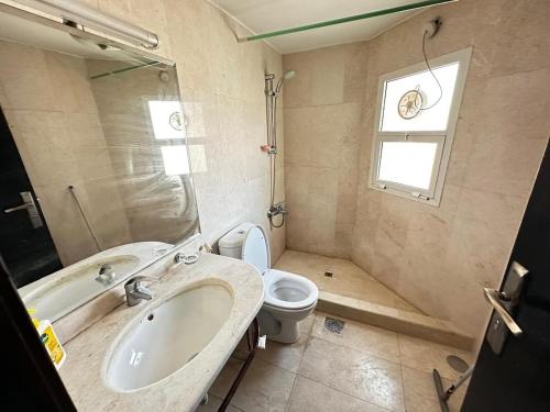 a bathroom with a sink and a toilet and a window at The Perfect Cozy Studio In Abu Dhabi in Abu Dhabi