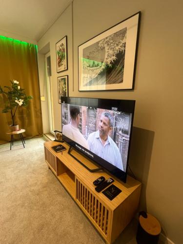 a flat screen tv sitting on a wooden stand in a living room at EUROPA22 - Hostel Coffee Home lub cały apartament in Tomaszów Mazowiecki