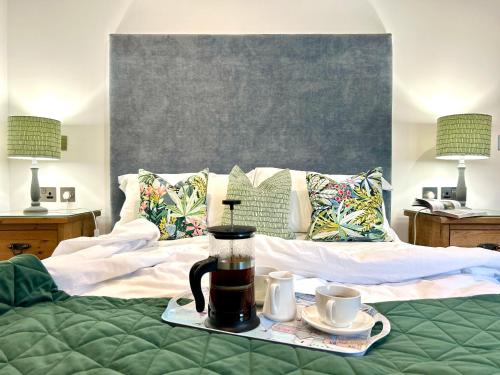 a bed with a coffee maker and two cups on it at Merlin Farm Cottages short walk to Mawgan Porth Beach and central location in Cornwall in Mawgan Porth