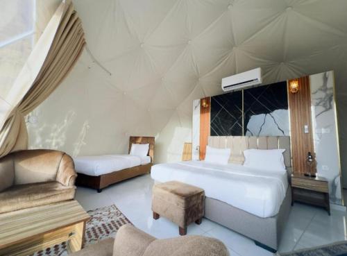 a bedroom with a large bed and a couch and a chair at Lunar Mirage Camp in Wadi Rum