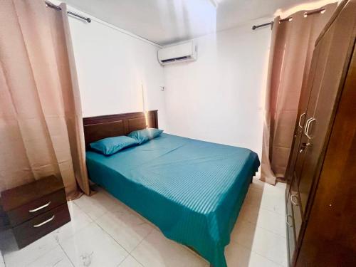 a small bedroom with a blue bed and a window at Soleil Couchant Apt 8 in Flic-en-Flac