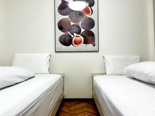 two beds in a room with a picture on the wall at Arusa-Ishite 2F in Matsuyama