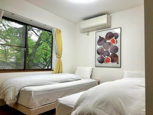 zwei Betten in einem Zimmer mit Fenster in der Unterkunft Arusa-Ishite 2F in Matsuyama