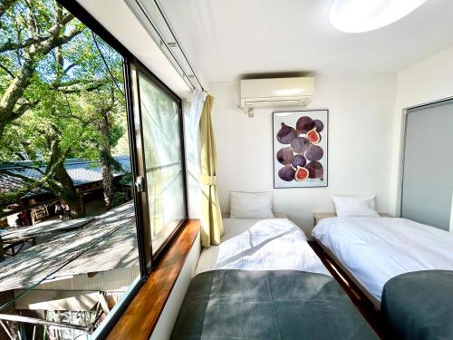 zwei Betten in einem Zimmer mit großem Fenster in der Unterkunft Arusa-Ishite 2F in Matsuyama