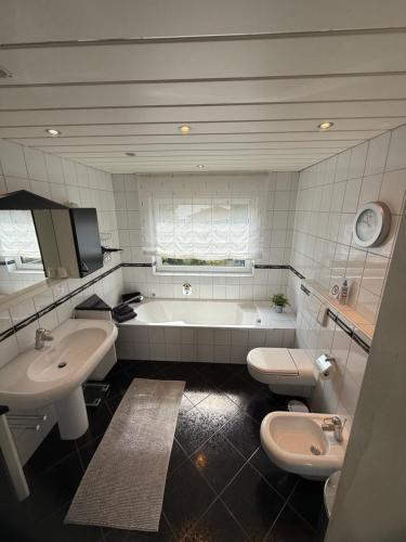 a bathroom with two sinks and a tub and two toilets at Himmelsleiter Ihr Rückzugsort mit Aussicht in Niederfischbach