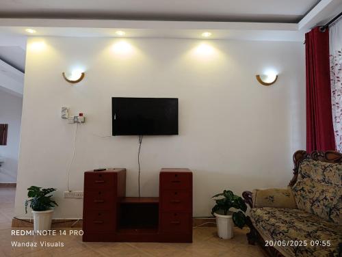 a living room with a couch and a television on a wall at Serviced 4 bedroom apartment in Mombasa