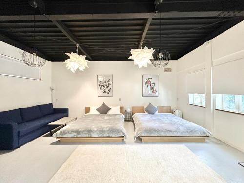 ein Schlafzimmer mit 2 Betten und einem blauen Sofa in der Unterkunft Arusa-Ishite 1F in Matsuyama