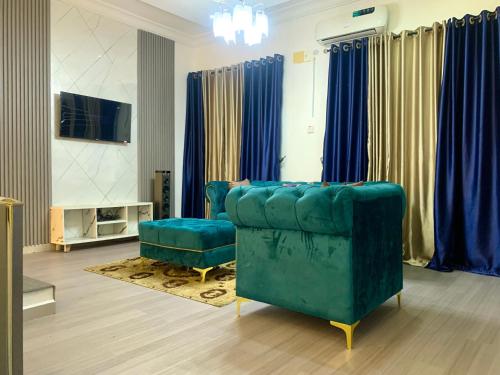 a living room with a green couch and a tv at Reagal Apartments, WMachine, WiFi, 13 mins DRV from Ikeja, OPIC ESTATE in Agege