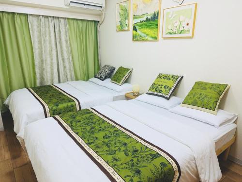 two beds in a room with green curtains at Shinjuku Downtown新宿 in Tokyo