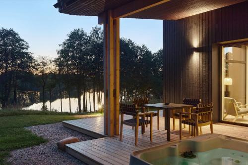 eine Terrasse mit einem Tisch, Stühlen und einer Badewanne in der Unterkunft Juoda Truoba 