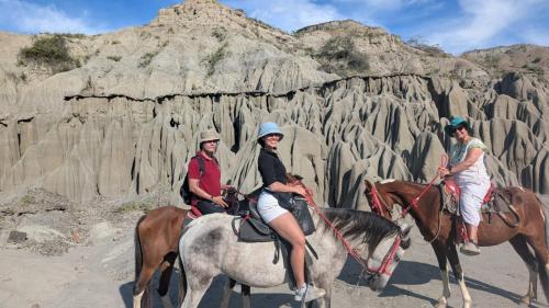 three people riding horses in front of a rock formation at Hotel Tatacoa Experience in Villavieja