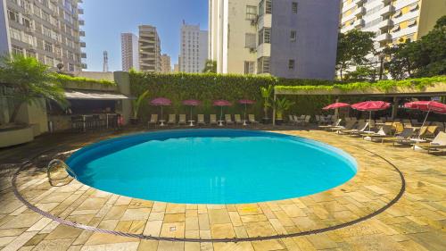 a large swimming pool with chairs and umbrellas at Ferraretto Guarujá Hotel & Spa in Guarujá
