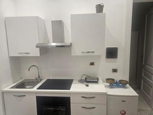 a white kitchen with a sink and a stove at Palazzo Gentile in Reggio Calabria
