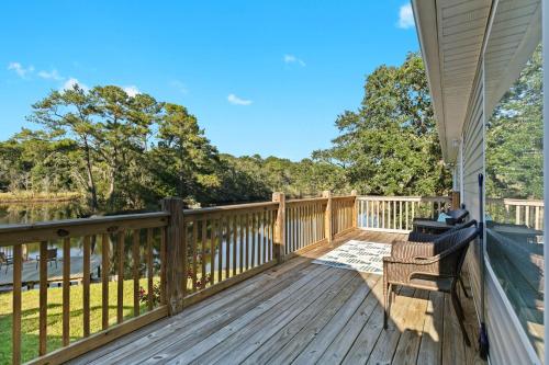 a deck with a chair and a view of the water at Tara's Riverfront Hideaway in Mobile