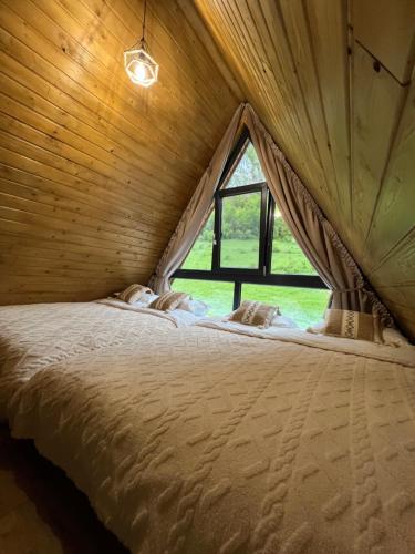 a bed in a wooden room with a window at A-Frame Retreat Vulcan in Vulcan